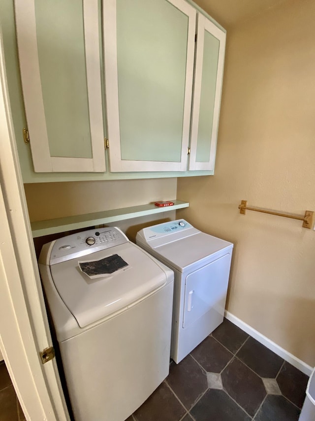 laundry area with washing machine and clothes dryer, cabinet space, baseboards, and dark tile patterned floors