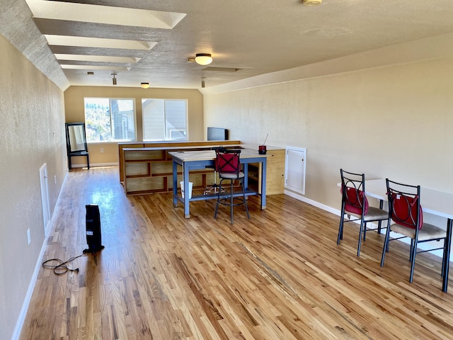 interior space featuring a ceiling fan, wood finished floors, baseboards, and a textured ceiling