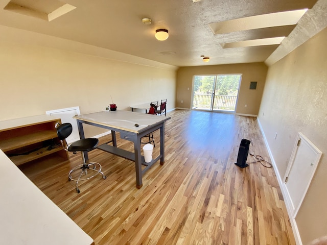 office with light wood-style floors, baseboards, and a textured ceiling