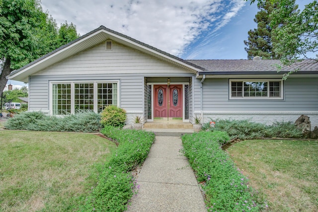 ranch-style house featuring a front yard and roof with shingles