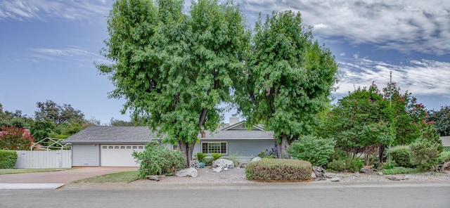 obstructed view of property featuring an attached garage, a chimney, fence, and concrete driveway