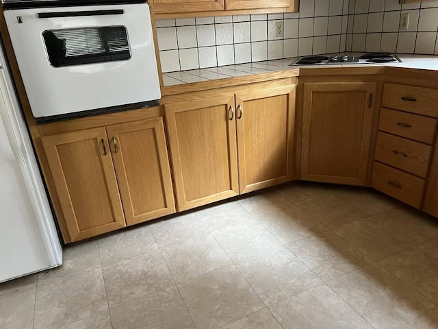 kitchen with gas cooktop, refrigerator, backsplash, tile counters, and oven