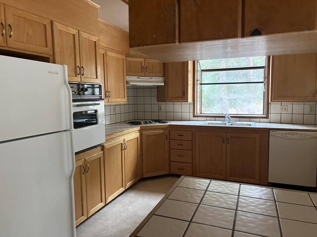 kitchen featuring backsplash, white appliances, tile counters, and sink