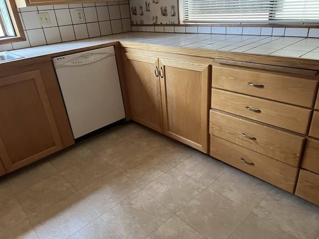 kitchen with white dishwasher, tile counters, and backsplash