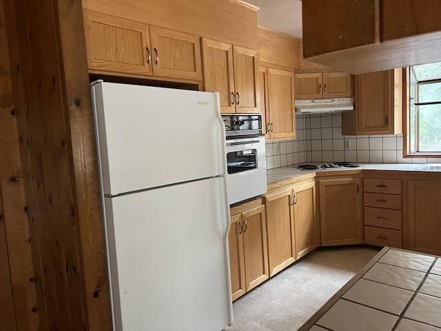 kitchen featuring white appliances, light tile patterned flooring, backsplash, and tile counters