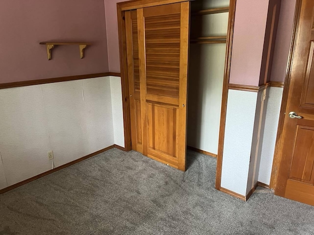 unfurnished bedroom with dark colored carpet and a closet