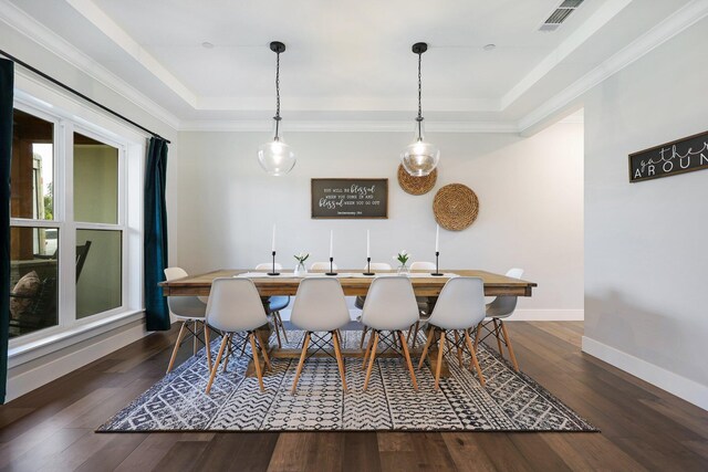 dining area featuring a tray ceiling, dark wood-type flooring, and ornamental molding