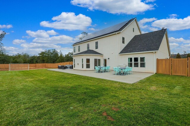 rear view of property featuring a patio, a yard, and solar panels