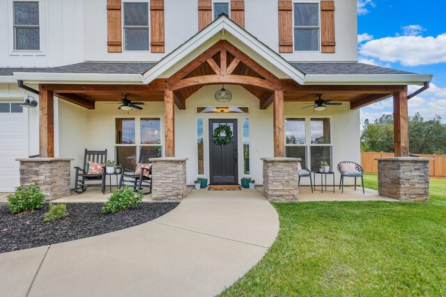 view of exterior entry with ceiling fan, a garage, and a yard