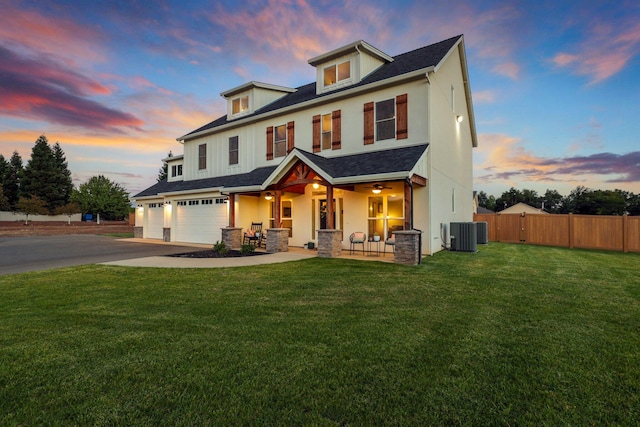 view of front of home featuring a garage, cooling unit, and a lawn