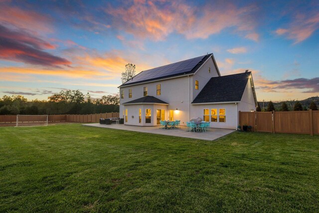 back house at dusk with a patio area and a yard