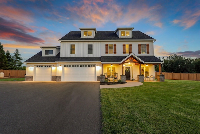 view of front of property featuring a garage, a yard, and covered porch