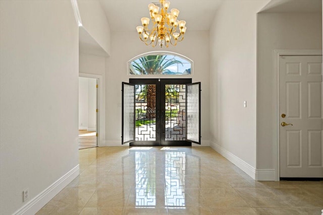 entrance foyer with french doors, a towering ceiling, and a notable chandelier