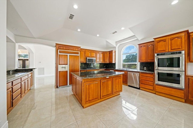 kitchen with decorative backsplash, a center island, light tile patterned flooring, and stainless steel appliances