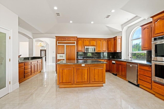 kitchen with a center island, lofted ceiling, sink, and appliances with stainless steel finishes