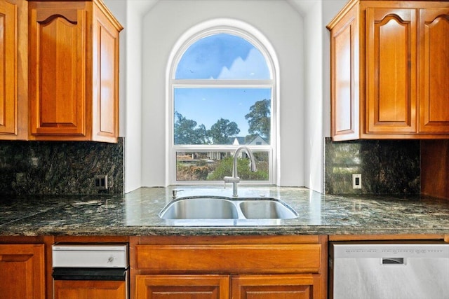 kitchen featuring tasteful backsplash, stainless steel dishwasher, dark stone countertops, and sink