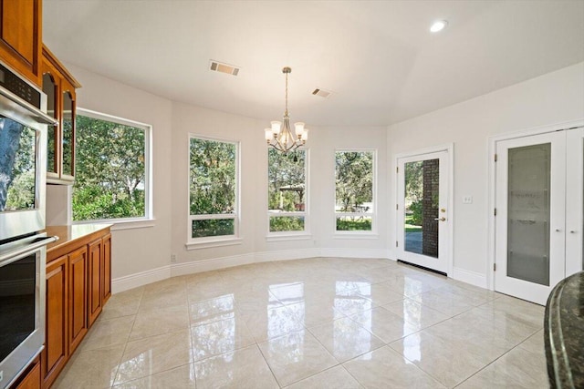 unfurnished sunroom featuring a notable chandelier and french doors