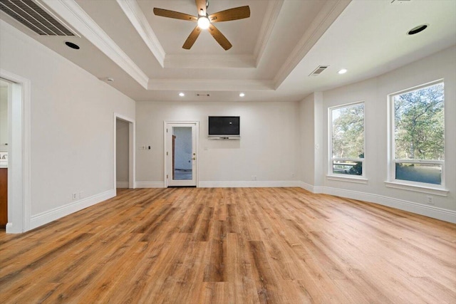 unfurnished living room with ceiling fan, a raised ceiling, crown molding, and light hardwood / wood-style flooring