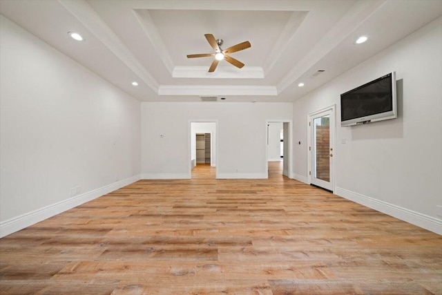 unfurnished living room with light wood-type flooring, a tray ceiling, ceiling fan, and ornamental molding