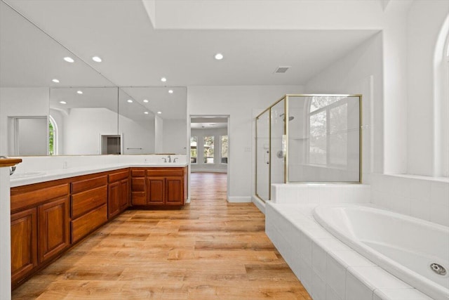 bathroom featuring plus walk in shower, hardwood / wood-style floors, and vanity