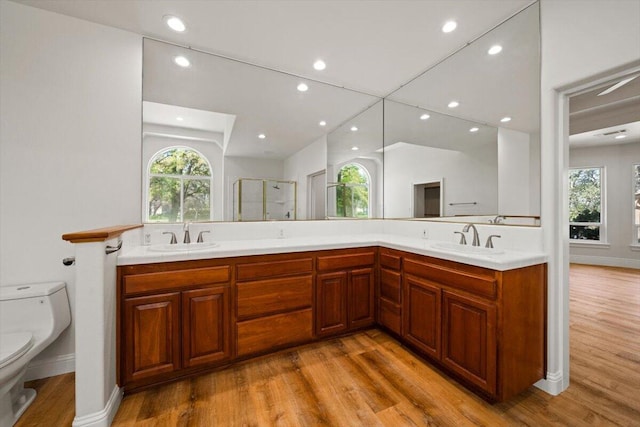 bathroom with hardwood / wood-style floors, vanity, toilet, and a shower with door