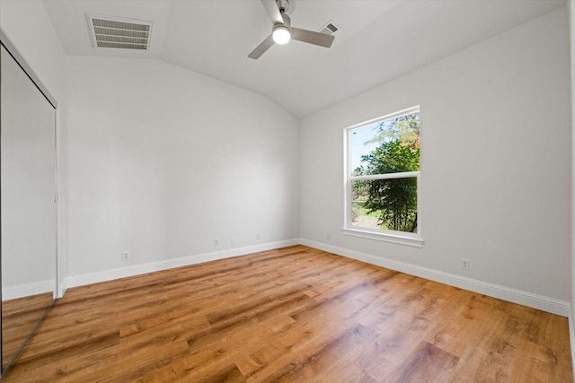 empty room with ceiling fan, hardwood / wood-style floors, and vaulted ceiling