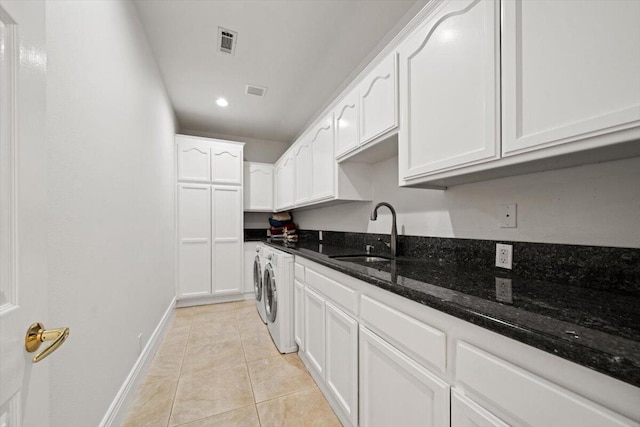 kitchen with white cabinetry, sink, dark stone counters, light tile patterned floors, and washer and dryer