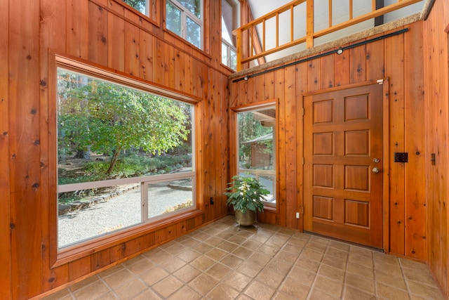 foyer with light tile patterned flooring and wood walls