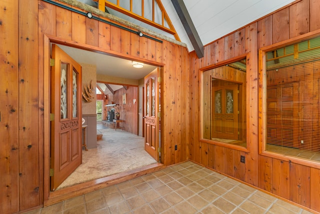 tiled entryway with wood walls and vaulted ceiling with beams