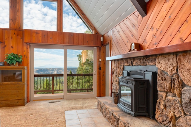 carpeted living room featuring high vaulted ceiling, wooden walls, beamed ceiling, and a wood stove