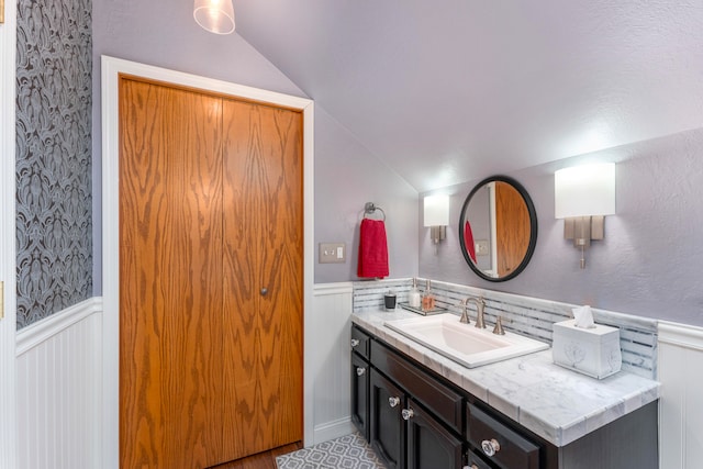 bathroom featuring decorative backsplash, vanity, and lofted ceiling