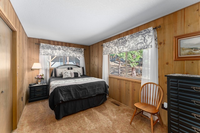 carpeted bedroom with wood walls and a textured ceiling