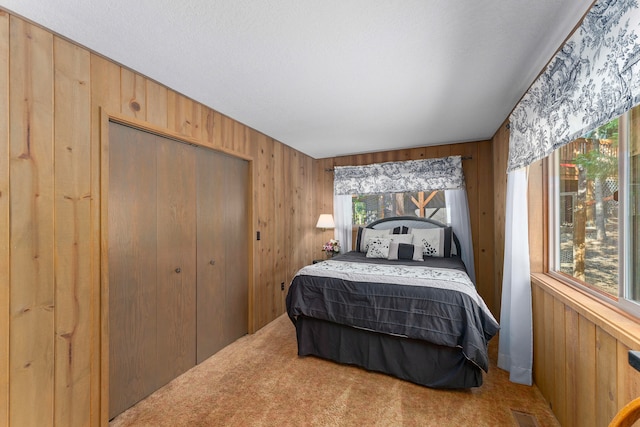 carpeted bedroom featuring multiple windows, wood walls, and a textured ceiling