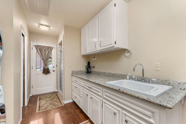 clothes washing area with sink and dark wood-type flooring