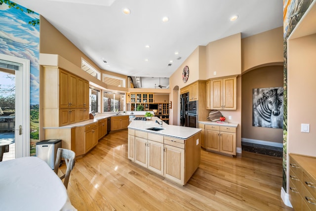 kitchen with wall oven, a kitchen island, high vaulted ceiling, light hardwood / wood-style floors, and dishwasher