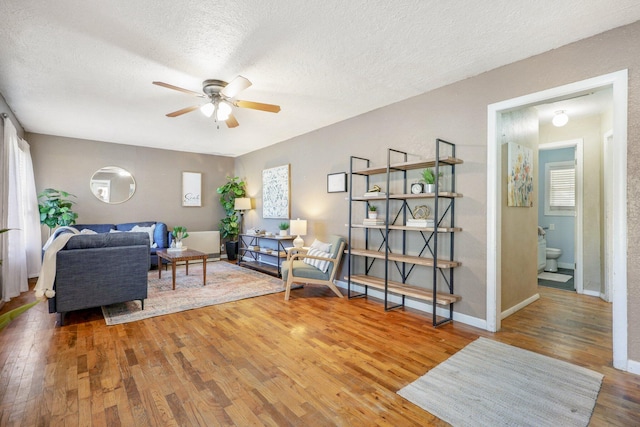 living room featuring a textured ceiling, wood-type flooring, and ceiling fan