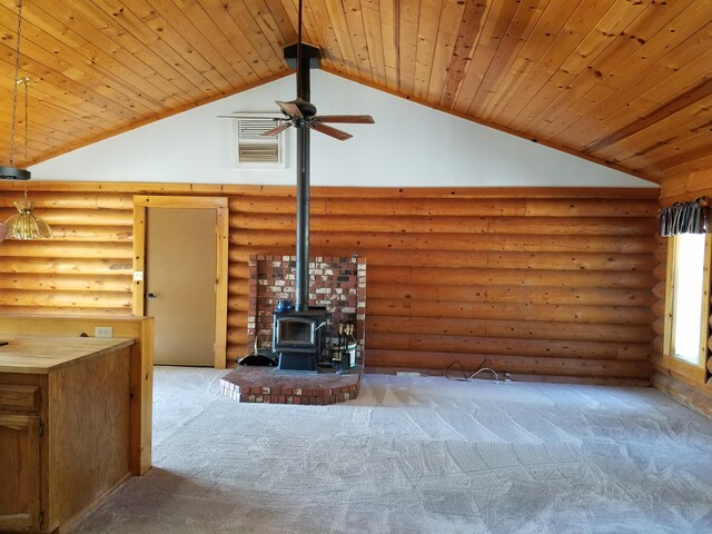 unfurnished living room featuring carpet floors, a wood stove, wood ceiling, and rustic walls