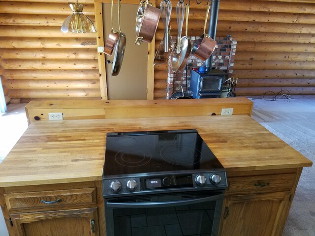 kitchen featuring carpet, rustic walls, and black range with electric stovetop