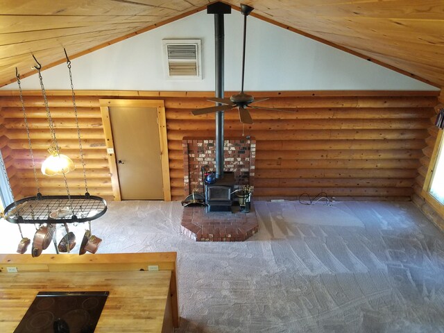 living room featuring carpet flooring, high vaulted ceiling, rustic walls, and a wood stove