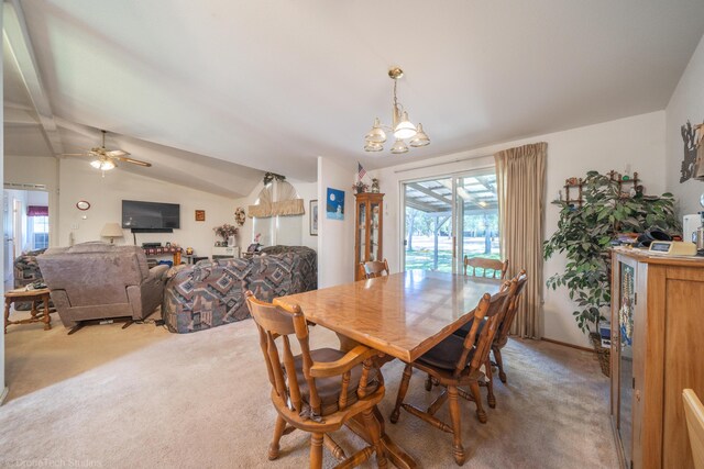 carpeted dining space with ceiling fan with notable chandelier and vaulted ceiling