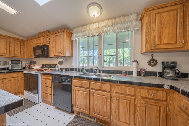 kitchen with lofted ceiling, black appliances, sink, and tile countertops