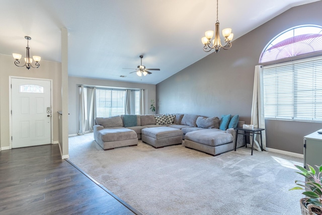 carpeted living room with ceiling fan with notable chandelier, vaulted ceiling, baseboards, and wood finished floors