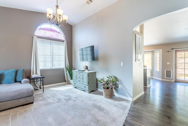 sitting room with baseboards, arched walkways, wood finished floors, vaulted ceiling, and a chandelier