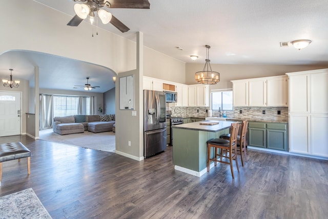 kitchen with appliances with stainless steel finishes, arched walkways, open floor plan, and white cabinetry