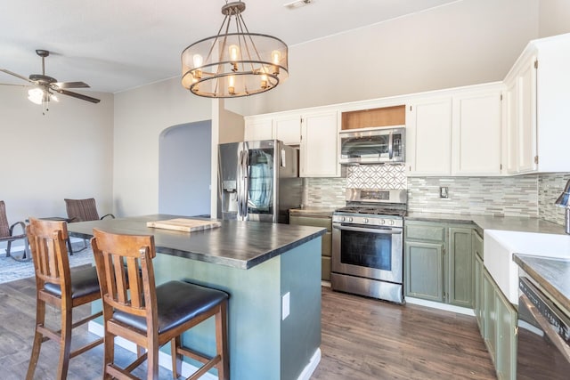 kitchen with white cabinets, tasteful backsplash, stainless steel appliances, and dark wood finished floors