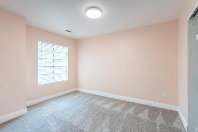 carpeted spare room featuring visible vents and baseboards