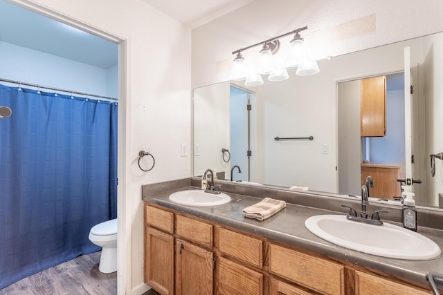 full bathroom featuring double vanity, a sink, toilet, and wood finished floors