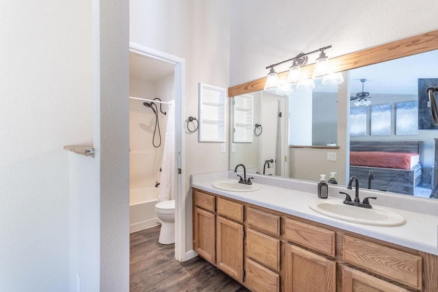 full bath with double vanity, wood finished floors, a sink, and toilet