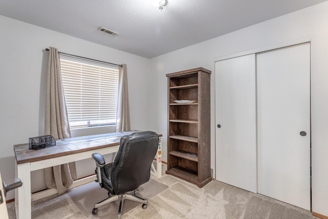 office featuring light carpet, a textured ceiling, and visible vents