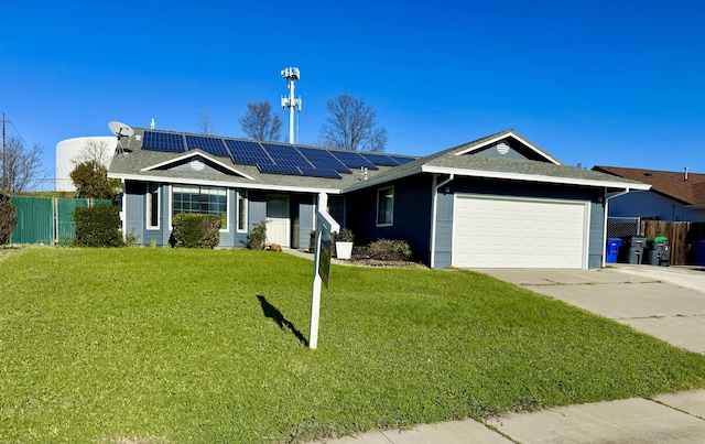 ranch-style home featuring solar panels, concrete driveway, an attached garage, a front yard, and fence